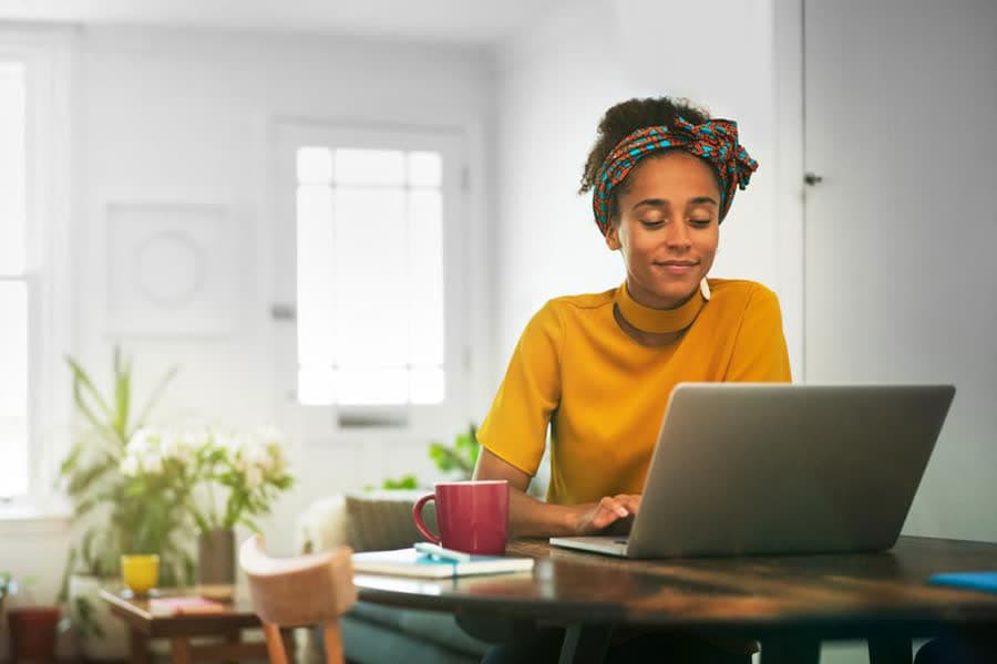 Vrouw die thuis aan tafel op haar laptop werkt